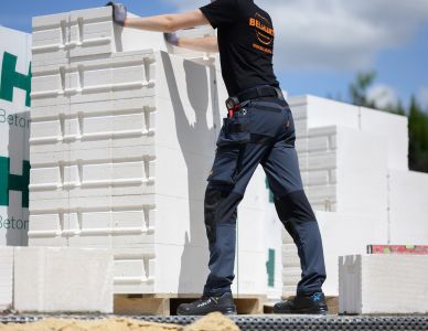 mężczyzna ubrany w spodnie robocze belhurt django stojący przy bloku styropianu